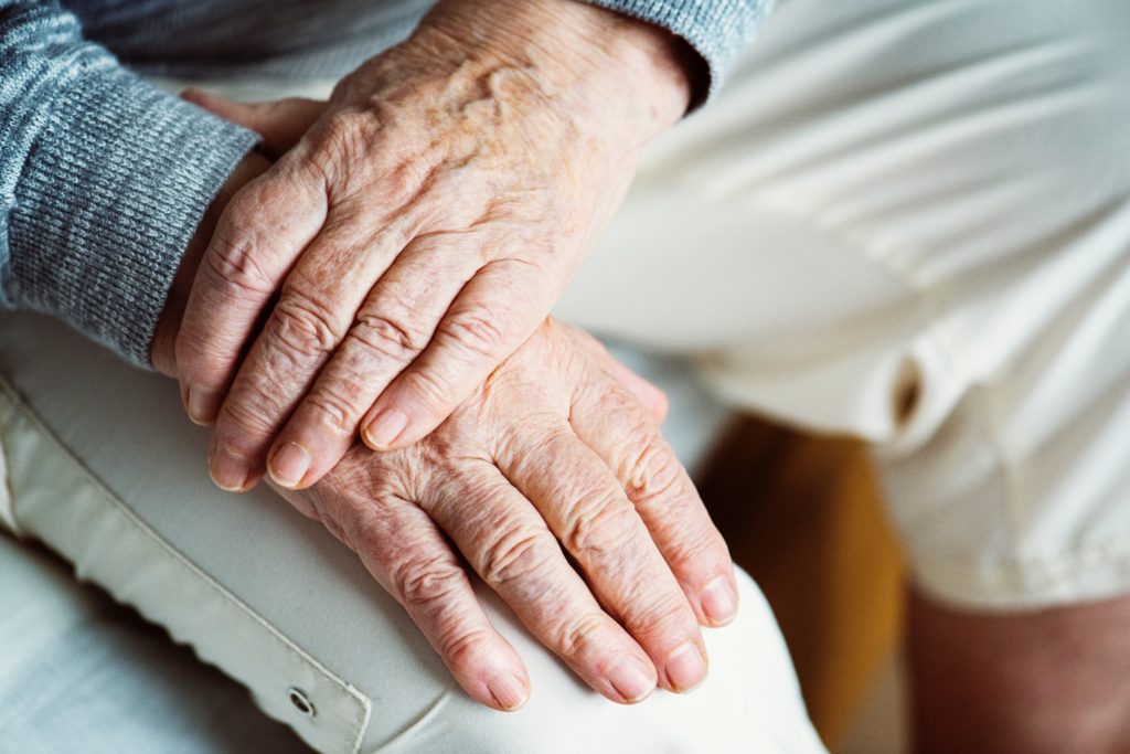 Close up of hands of an aging person resting on their knees