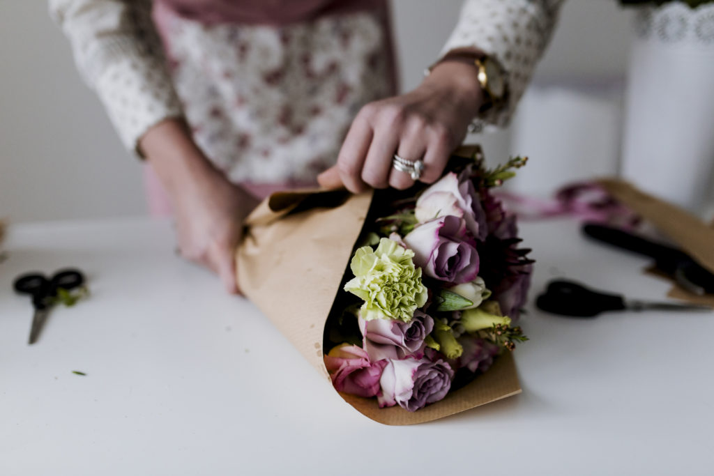 close-up photo of a florists hands wrapping a bouquet of flowers