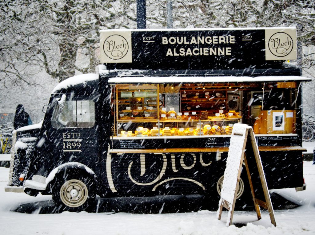 black bakery food truck parked in snowy winter scene