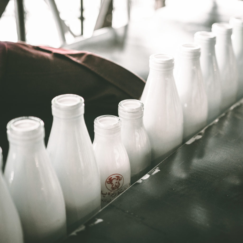 photo of white glass milk bottles lined up in a row